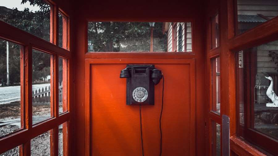 Suchmaschinenoptimierung Hannover - In einer roten Telefonzelle aus Holz hängt ein altmodisches Wählscheibentelefon. Die Zelle ist mit Glasfenstern ausgestattet, die den Blick nach draußen ermöglichen. Man sieht ein Teilbild eines Gebäudes und einiger Bäume, ganz ähnlich dem zeitlosen Charme, den man beim Erstellen einer Webvisitenkarte sucht. Local SEO Agentur Hannover.