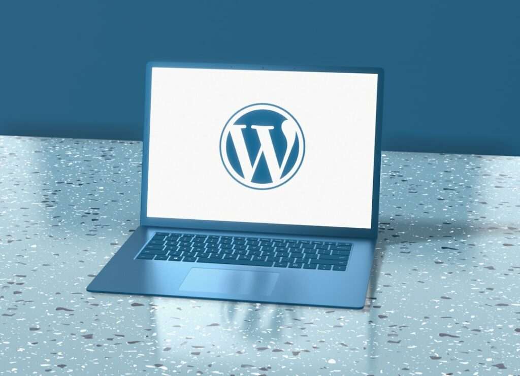 Suchmaschinenoptimierung Hannover - Ein Laptop mit einem auf dem Bildschirm angezeigten WordPress-Logo steht auf einer Terrazzooberfläche. Der Hintergrund ist blau und das auf der Oberfläche reflektierte Licht erzeugt einen subtilen Schatten unter dem Laptop. Perfekt für alle, die mühelos eine „Webvisitenkarte erstellen“ möchten. Local SEO Agentur Hannover.