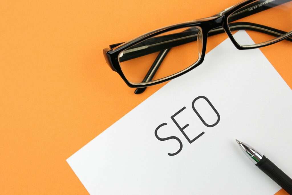 Reading glasses and blank with word SEO on a orange background