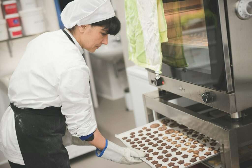 Baker placing tray of star-shaped cookies into oven