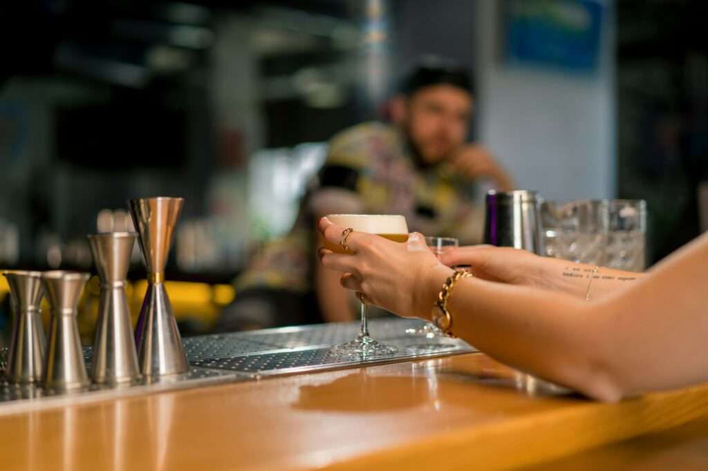 bar customer's hand taking an alcoholic cocktail from the bar drinks concepts in bar or club