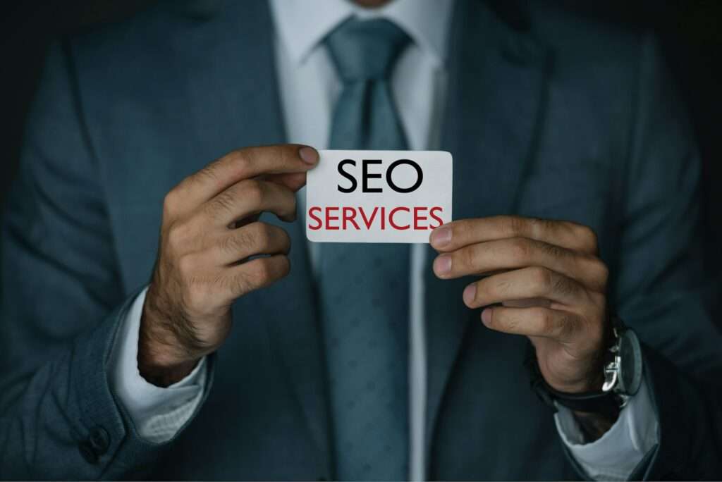 SEO Hannover - Eine Person im Anzug hält eine Karte mit der eleganten Aufschrift „Google SEO Services“. Local SEO Agentur Hannover.