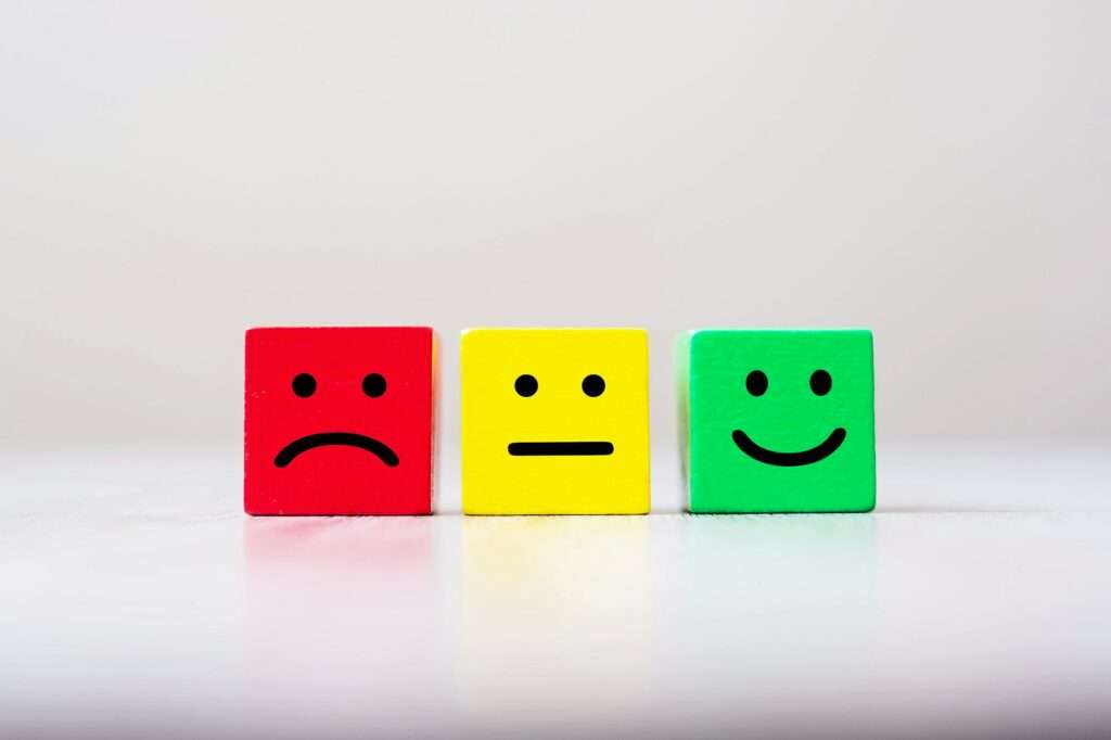 Emotion face symbol on yellow wooden cube blocks. Service rating, ranking, customer review