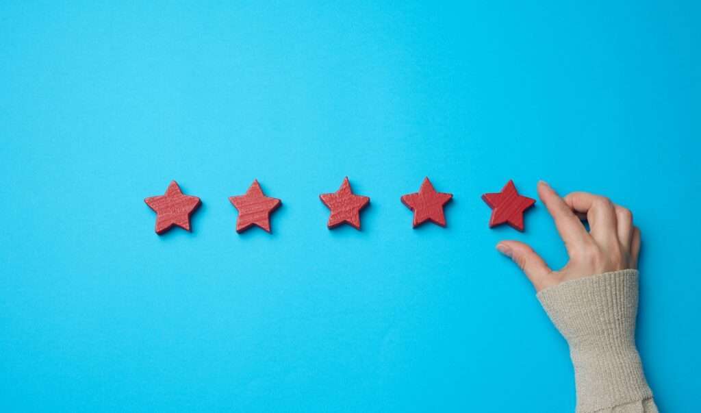 Five red stars and a hand on a blue background. Evaluation of the quality of services and goods