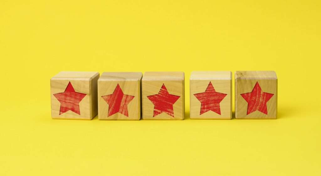 Five wooden cubes with a red star on a yellow background. Quality assessment concept