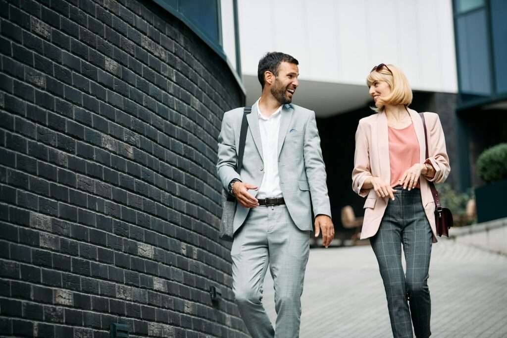 Happy business colleagues talking while walking through the city.