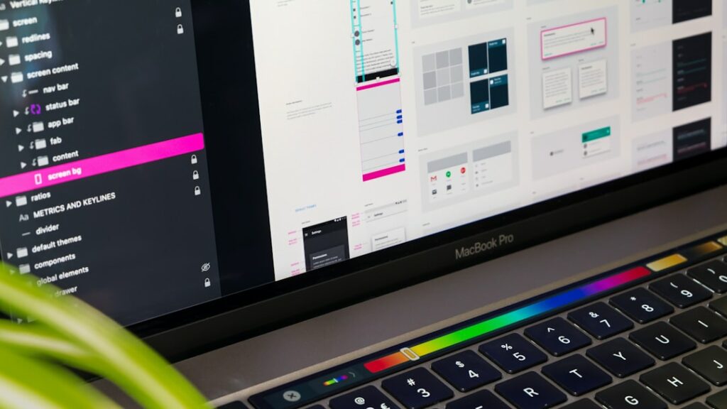 SEO Hannover - Auf einem MacBook Pro wird ein Bildschirm mit verschiedenen UI-UX-Designelementen angezeigt, darunter Layouts, Schaltflächen und Grafiken. Im Vordergrund ist ein kleiner Teil einer grünen Pflanze zu sehen. Local SEO Agentur Hannover.