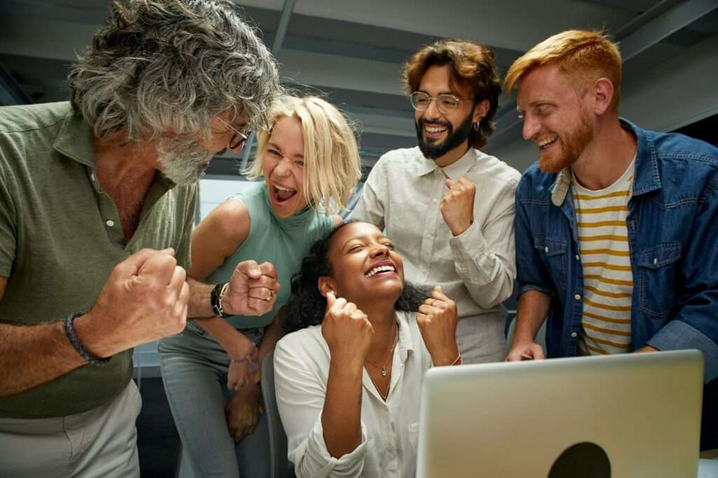 In the modern office a group of colleagues of different ages and ranks celebrate a business success.