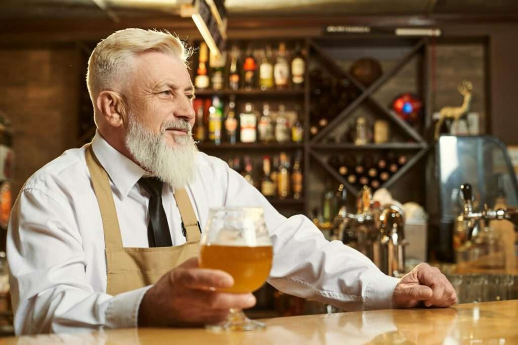 Male brewer standing over bar and smiling