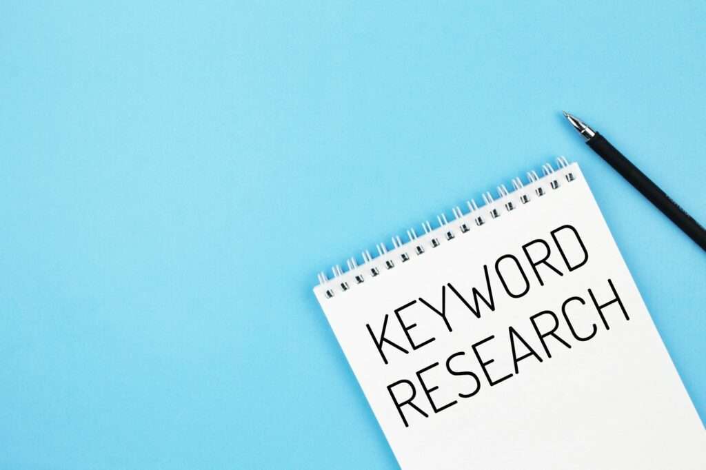 Pen and notebook with word keyword research on a blue background