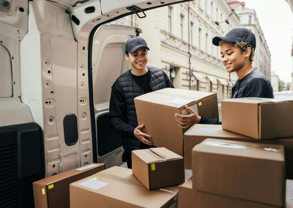 People working for a delivery company. Couriers load packages into a car.