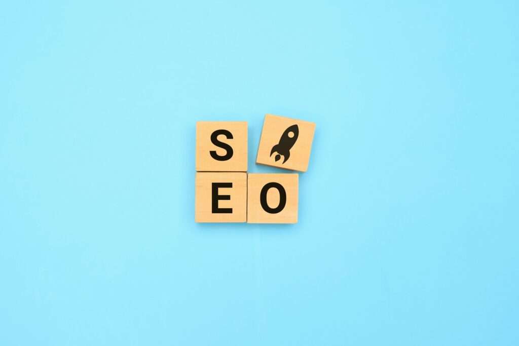 SEO Hannover - Vier Holzkacheln auf blauem Hintergrund ergeben das Wort „SEO“, wobei auf der vierten Kachel ein Raketensymbol zu sehen ist, das die Leistungsfähigkeit von Google SEO symbolisiert. Local SEO Agentur Hannover.