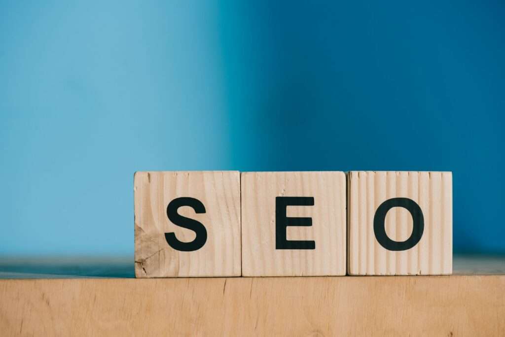 SEO word made from wooden blocks on blue background. Search engine optimization