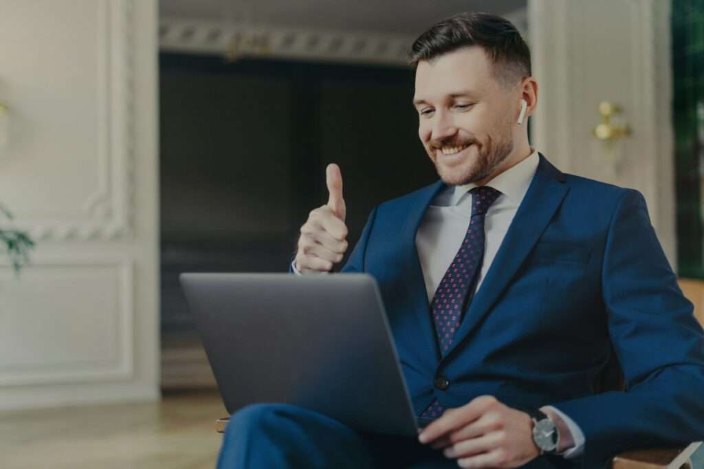 Successful businessman in suit showing thumb up during video call