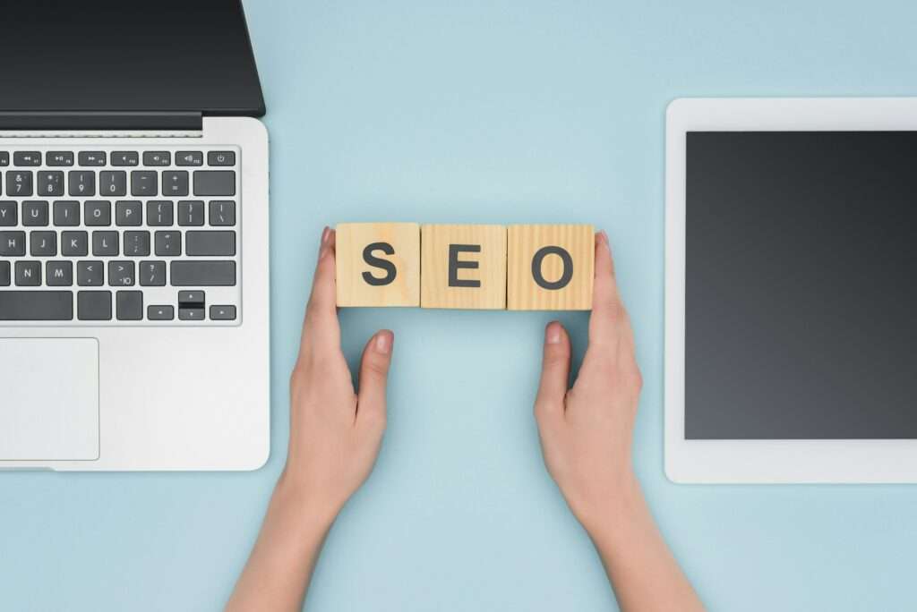 Top view of female seo manager holding cubes near gadgets on light blue background