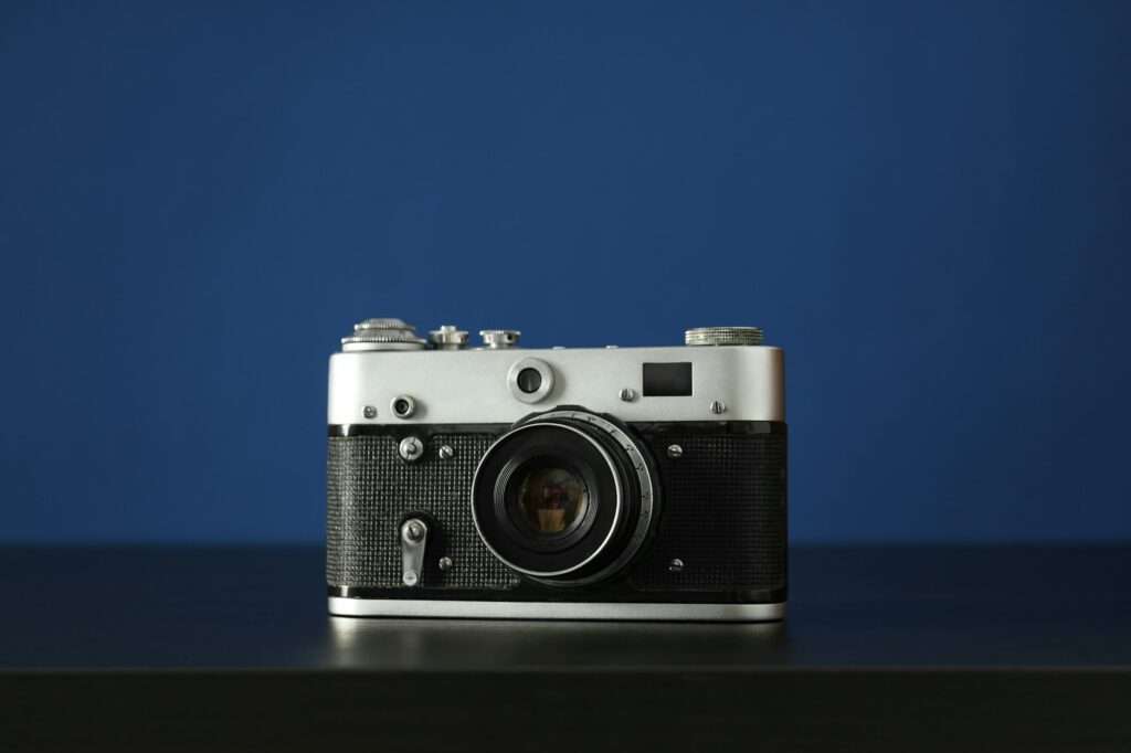 Vintage camera on wooden table on blue background, close up