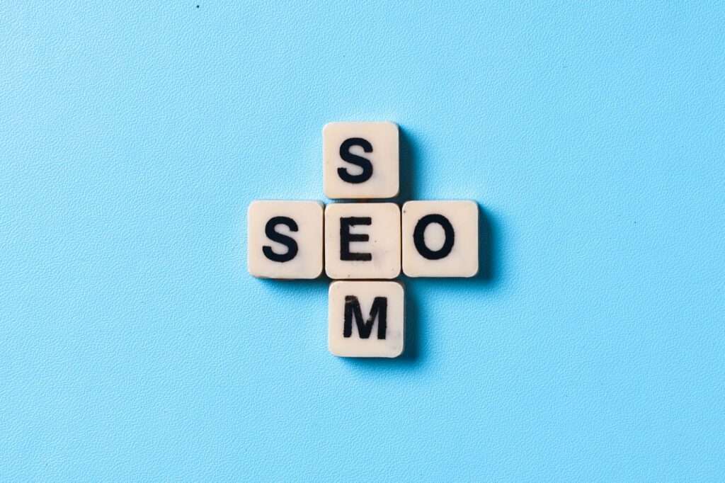 SEO Hannover - Vier kreuzförmig angeordnete Scrabblesteine auf blauem Hintergrund ergeben das Wort „SEMO“. Das Wort „SEM“ ist vertikal und horizontal angeordnet. Local SEO Agentur Hannover.