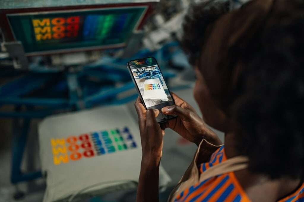 Close up of interracial printing shop worker taking picture of t-shirt