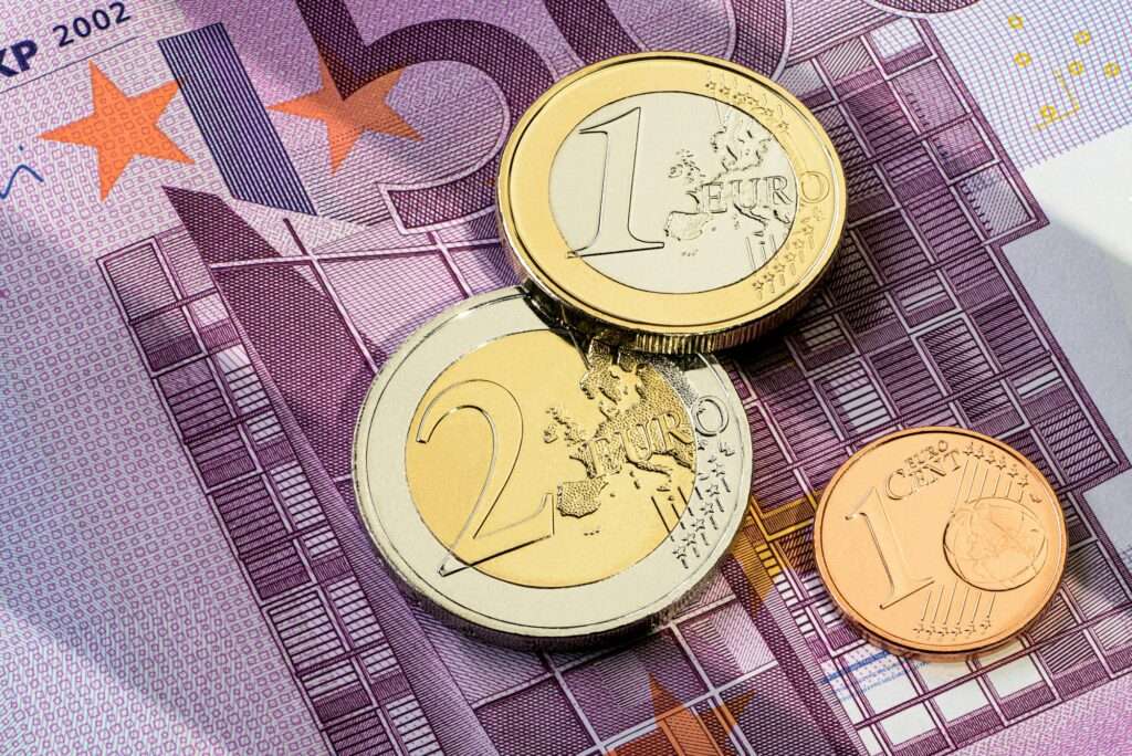 Webdesign Hannover - Nahaufnahme der Euro-Währung, mit einer 50-Euro-Banknote unter einer 1-Euro-Münze, einer 2-Euro-Münze und einer 1-Cent-Münze. Die Banknote zeigt Architekturbilder, während die Münzen Karten und Symbole zeigen – wichtige Hilfsmittel bei der Beantwortung von Fragen wie „Was kostet eine Landingpage?“ Local SEO Agentur Hannover.