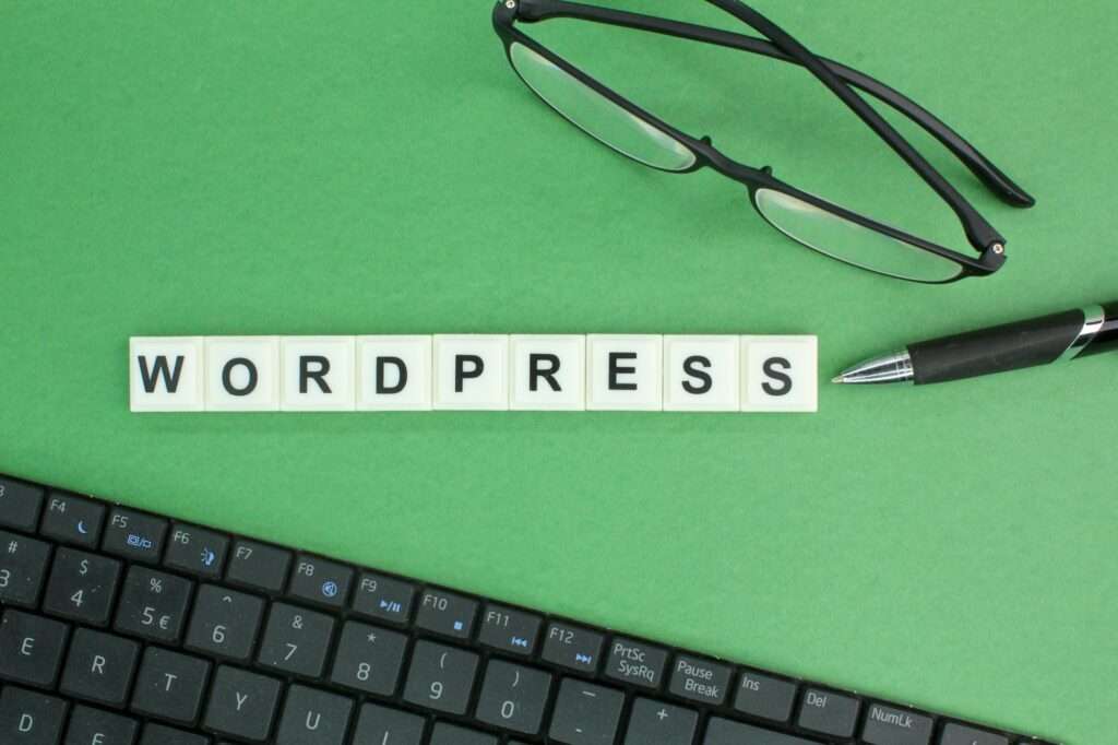 SEO Hannover - Auf einem grünen Hintergrund ist in Buchstabenkacheln das Wort „WordPress“ dargestellt, flankiert von einer schwarzen Brille, einem Stift und einer teilweisen Tastaturansicht. Dies weckt die Neugier mit der versteckten Frage: „Was ist ein Theme in WordPress?“ Local SEO Agentur Hannover.