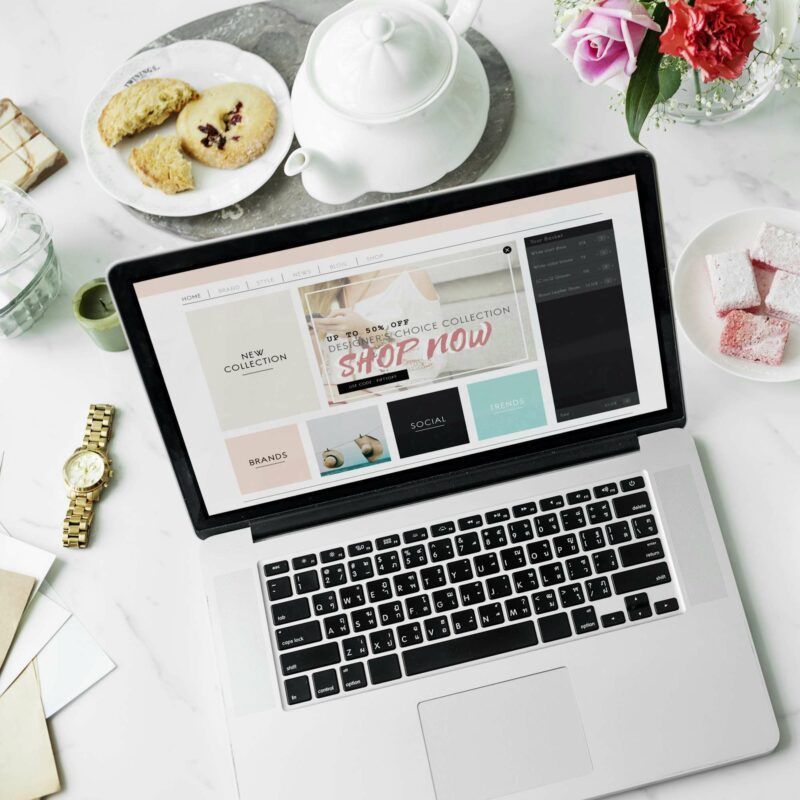 Webdesign Hannover - Auf einem Marmortisch steht ein Laptop mit der Website „Erstellung“. Daneben sorgen ein Teller mit Keksen, eine Teekanne mit Tasse und ein Strauß rosa Rosen für Charme. Eine goldene Uhr und Zuckerwürfel in einer Schüssel vervollständigen die Szene, während neben der Uhr Umschläge bereitliegen. Local SEO Agentur Hannover.