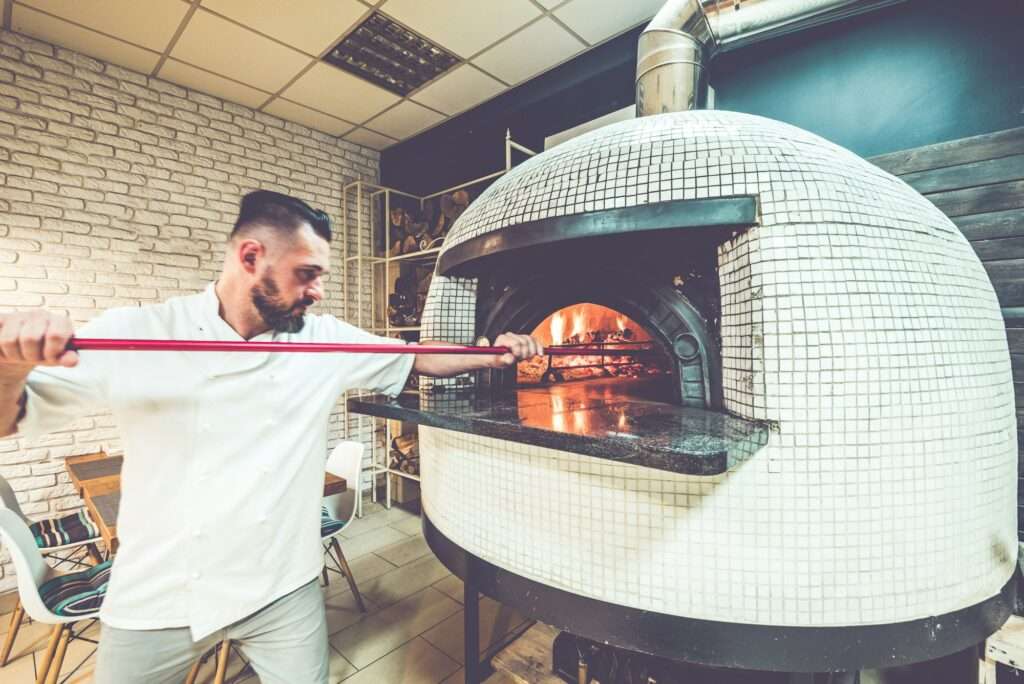 Pizza chef in action at local pizzeria business