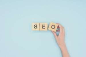 Top view of female seo manager holding cube with seo lettering on light blue background