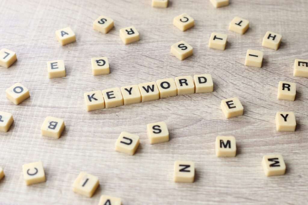 Webdesign Hannover - Scrabble-Steine sind so angeordnet, dass sie auf einer Holzoberfläche das Wort „KEYWORD“ ergeben, umgeben von verstreuten Buchstaben, die darauf aus zu sein scheinen, Wörter zu bilden. Es erinnert an die Verwendung von Google Keywords, um die ultimative Worträtsel-Strategie freizuschalten. Local SEO Agentur Hannover.