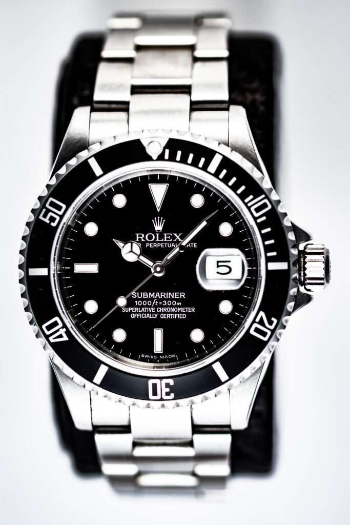 Webdesign Hannover - Eine Nahaufnahme einer Rolex Submariner-Armbanduhr mit Edelstahlarmband, schwarzer Lünette und schwarzem Zifferblatt, das 10:13 Uhr und das Datum als 5. anzeigt, elegant auf einem schwarzen Kissen positioniert – aufgenommen von einem Werbefotografen aus Hannover. Local SEO Agentur Hannover.